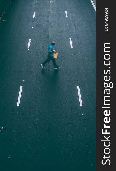 A man crossing an empty street. A man crossing an empty street.