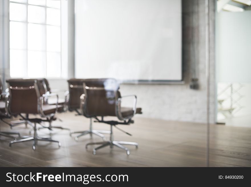 Empty chairs in a business conference room with whiteboard in background.