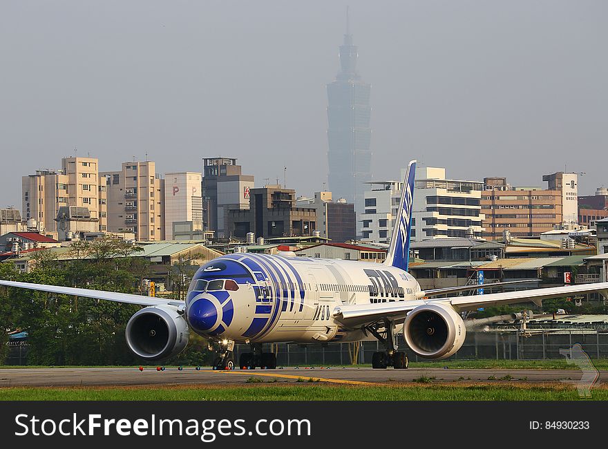 An airplane on a runway and buildings in the background. An airplane on a runway and buildings in the background.