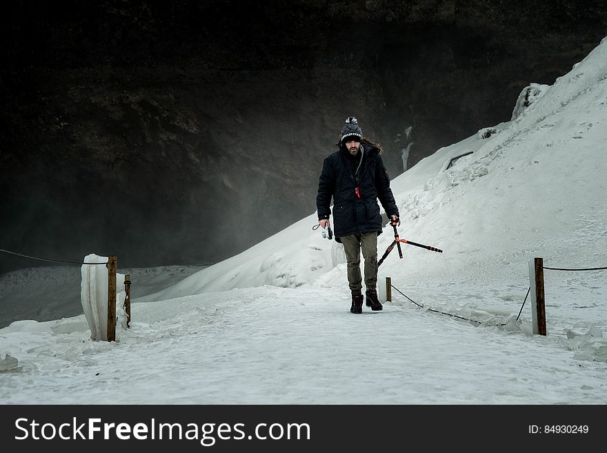 Man Wearing Black Jacket Brown Jeans and Black Shoes Walking on Snow