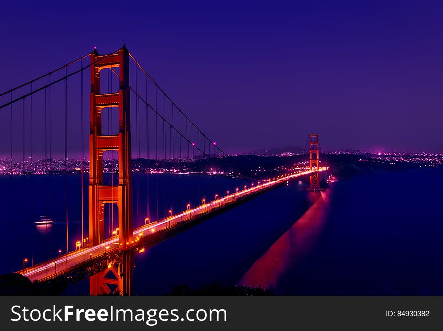 The Golden Gate Bridge by night and its reflection on the river surface.