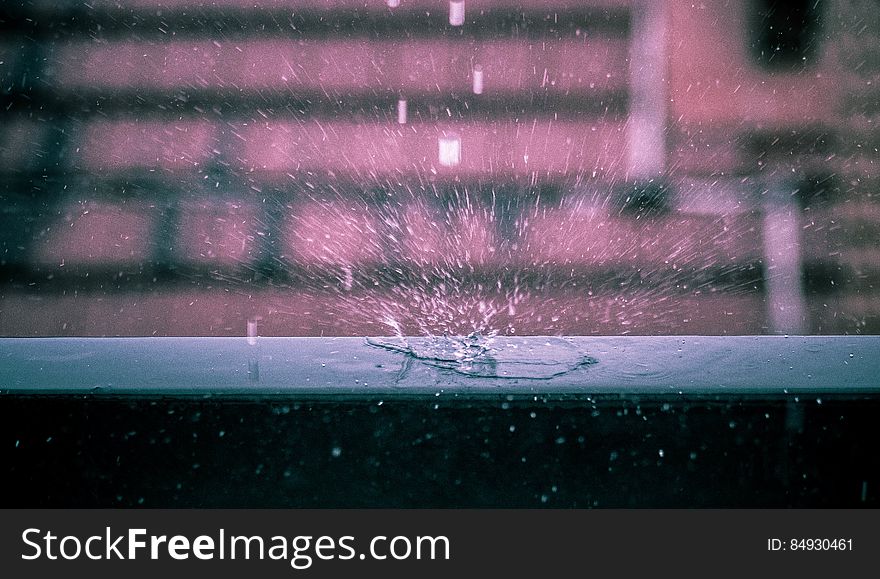 A close up of rain drops falling on a window seal. A close up of rain drops falling on a window seal.