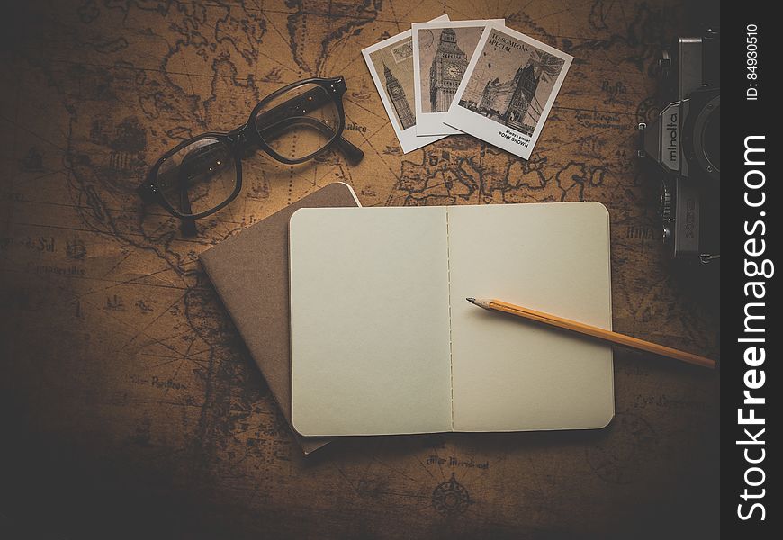 Black Framed Eyeglasses Beside Big Ben Pictures and Notebook