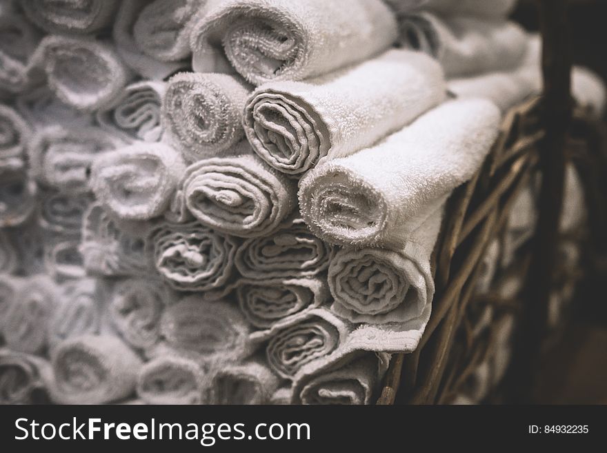 Stack of rolled white bathroom towels in basket.