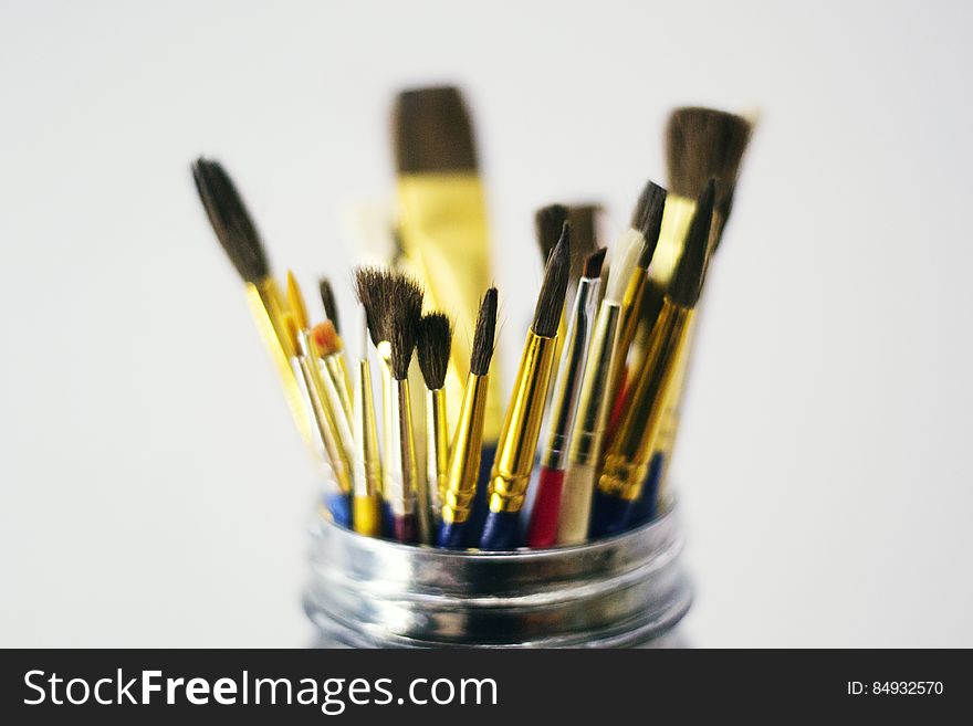 A close up of different paint brushes in a metal holder.