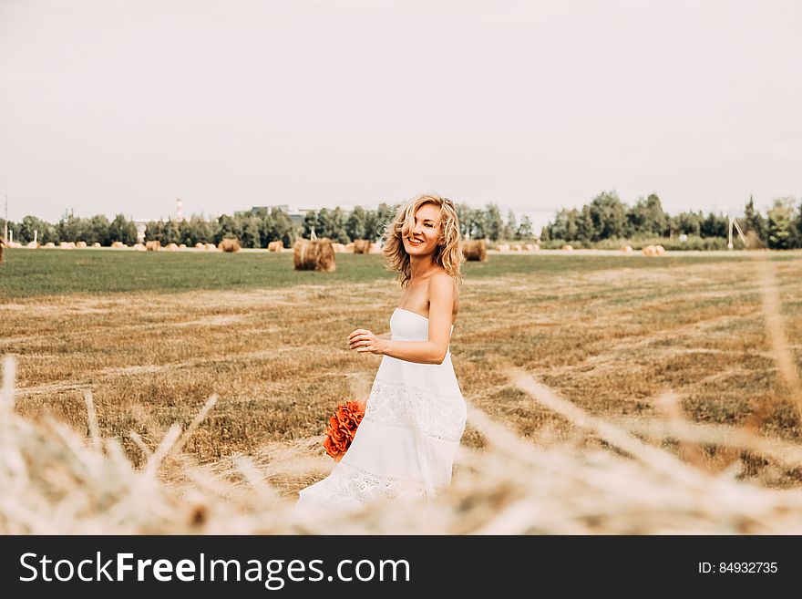 A woman wearing a white dress outdoors on a harvested field. A woman wearing a white dress outdoors on a harvested field.
