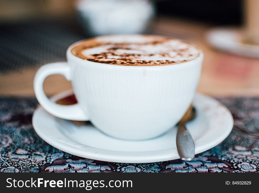 A cup of coffee with milk foam and cinnamon or cacao powder on top.