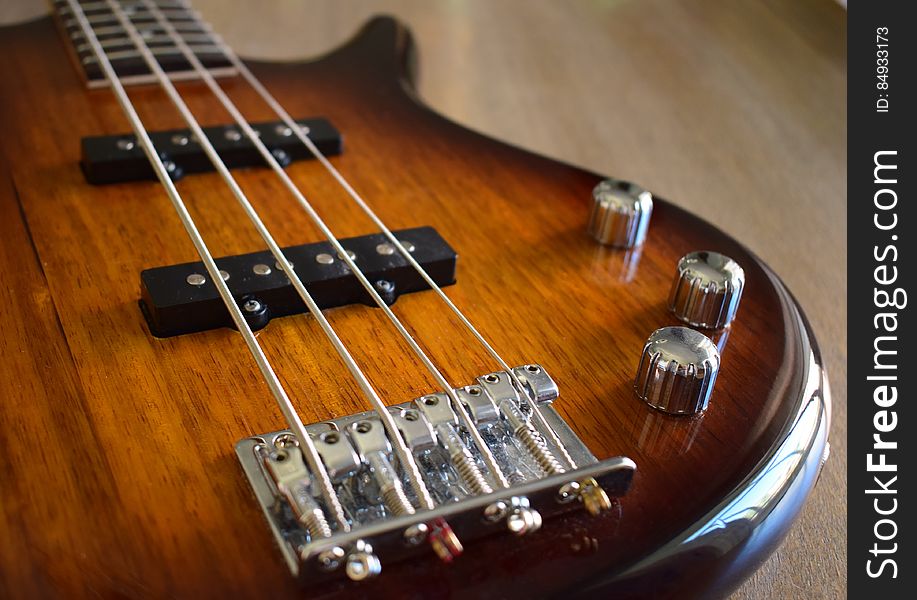 Close up of a glossy wood guitar with chrome dials.