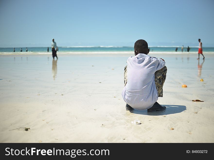 A boy sits on Lido beach in Mogadishu, Somalia, as people swim in the water and walk along the beach on April 15. Despite the continued threat of al Shabaab in Somalia, much of daily life in Mogadishu has returned to normal. AU UN IST / TOBIN JONES. A boy sits on Lido beach in Mogadishu, Somalia, as people swim in the water and walk along the beach on April 15. Despite the continued threat of al Shabaab in Somalia, much of daily life in Mogadishu has returned to normal. AU UN IST / TOBIN JONES.