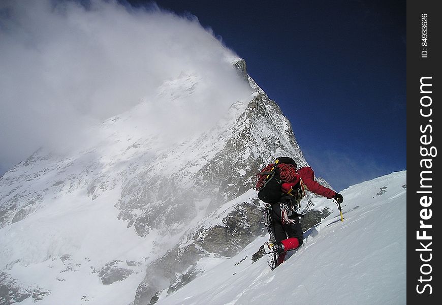 A mountain climber on a steep snowy hill with snow.