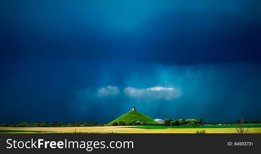 A monument on a green hill with dark stormy skies. A monument on a green hill with dark stormy skies.