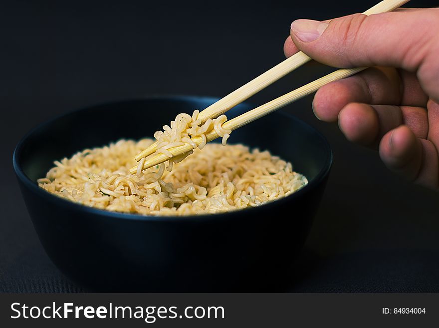 Person Holding a Chopsticks and Picking a Noodles in Black Bowl