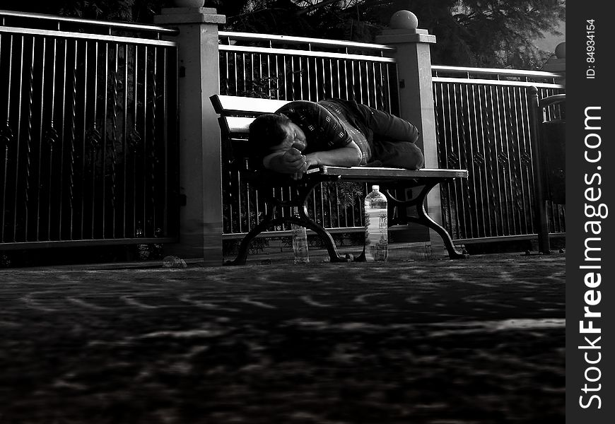 A man sleeping on a park bench. A man sleeping on a park bench.