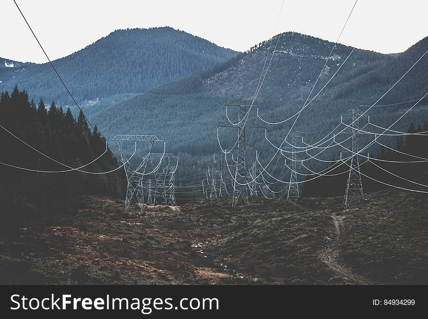 Electricity pylons receding with forested mountains in background. Electricity pylons receding with forested mountains in background.