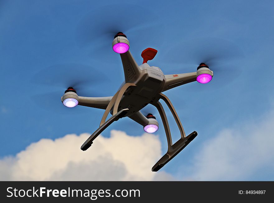 Underside view of quadcopter drone with flight with blue sky and cloudscape background. Underside view of quadcopter drone with flight with blue sky and cloudscape background.