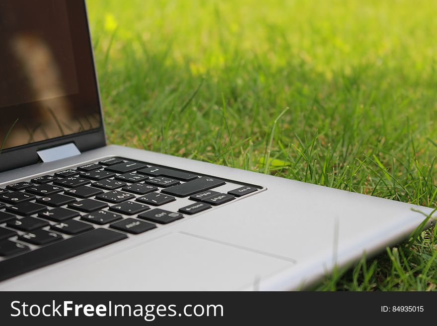 Open laptop computer on grass lawn or field. Open laptop computer on grass lawn or field.