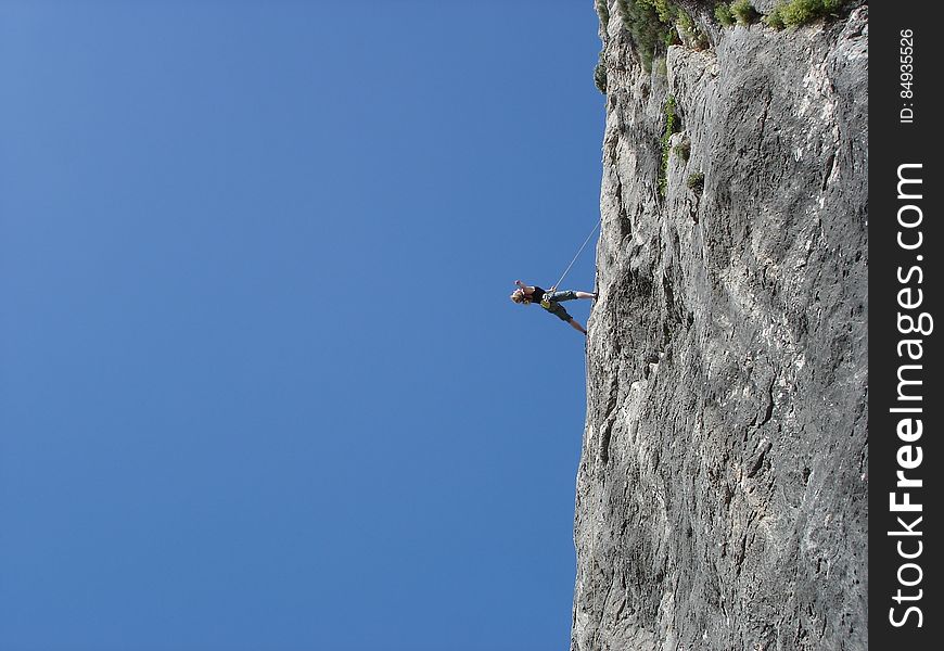 Man Standing on Rock Against Clear Blue Sky