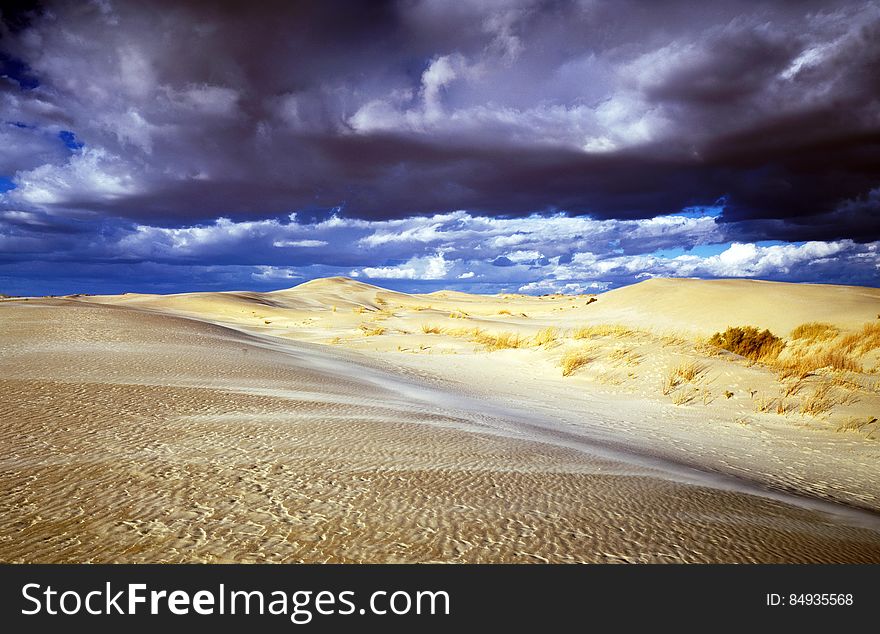 Dark storm clouds over sand dunes in desert landscape. Dark storm clouds over sand dunes in desert landscape.