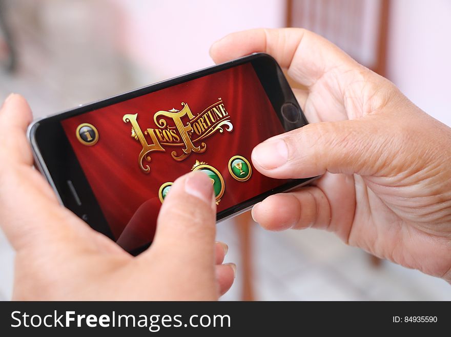Hands of a person using a gaming app on a mobile phone. Hands of a person using a gaming app on a mobile phone.