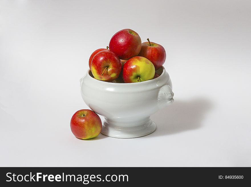 Ceramic bowl of fresh red and green apples, white studio background. Ceramic bowl of fresh red and green apples, white studio background.