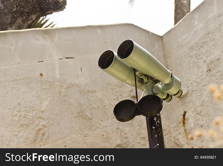 Binoculars on a stand in front of a wall. Binoculars on a stand in front of a wall.