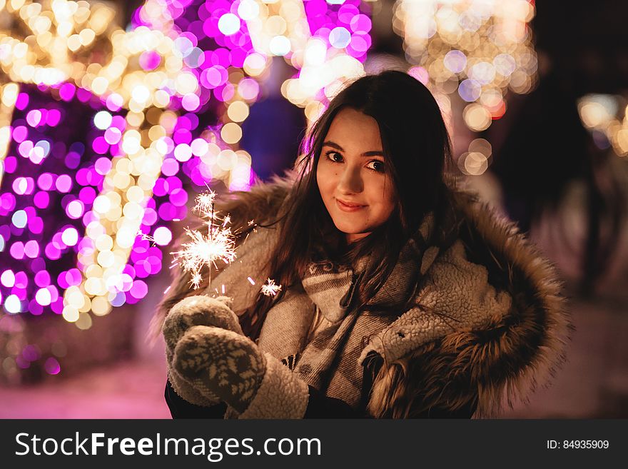 A portrait of a young woman in winter clothes holding a sparkler. A portrait of a young woman in winter clothes holding a sparkler.