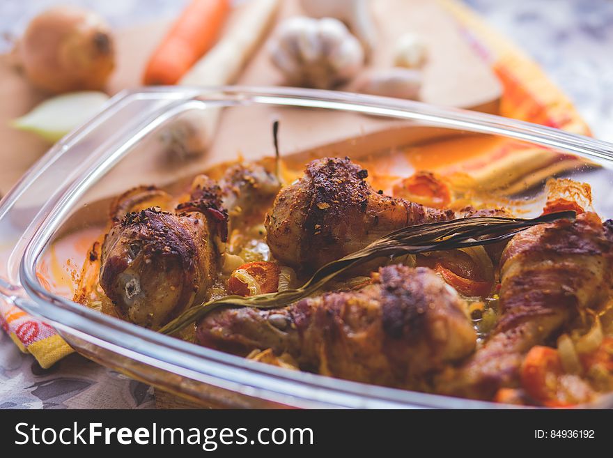 Roast chicken drumsticks with vegetables in a refractory bowl.