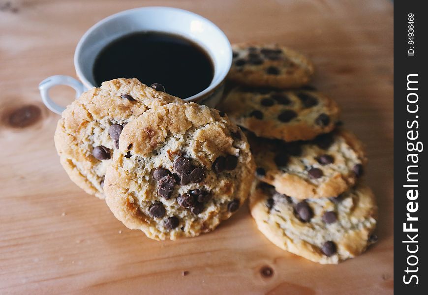 A close up of a cup of coffee and chocolate chip cookies. A close up of a cup of coffee and chocolate chip cookies.
