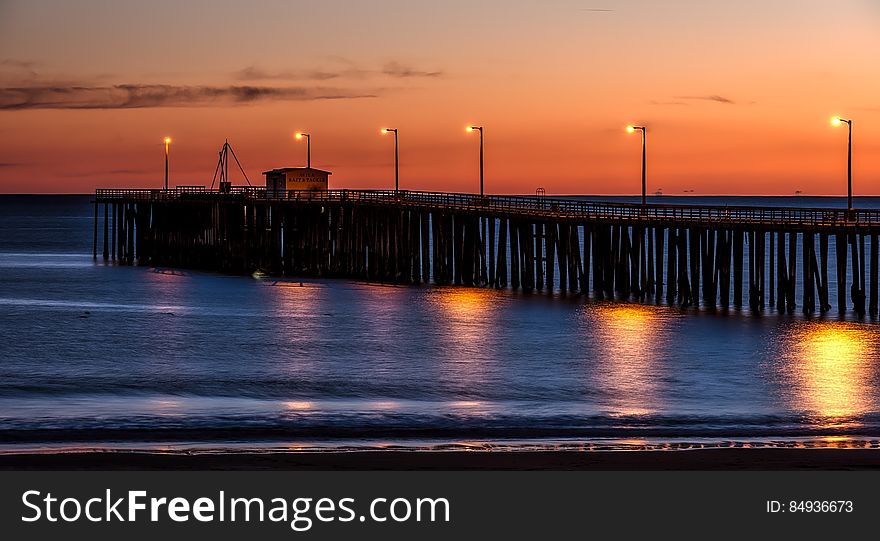 Wooden Dock on Sea Shore With Light Post during Sunset