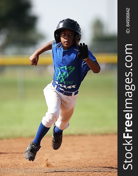 Boy in Blue and White Baseball Jersey Running on Brown Soil Field during Daytime
