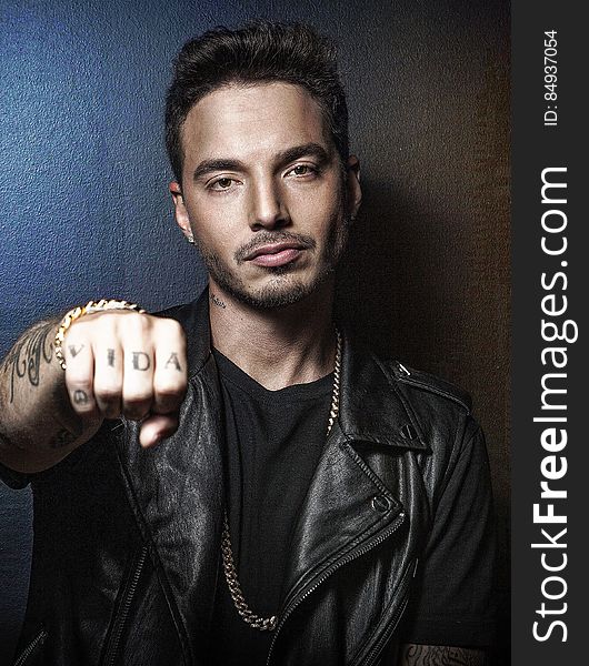 A portrait of J Balvin showing his right fist with vida tattoo on it. A portrait of J Balvin showing his right fist with vida tattoo on it.