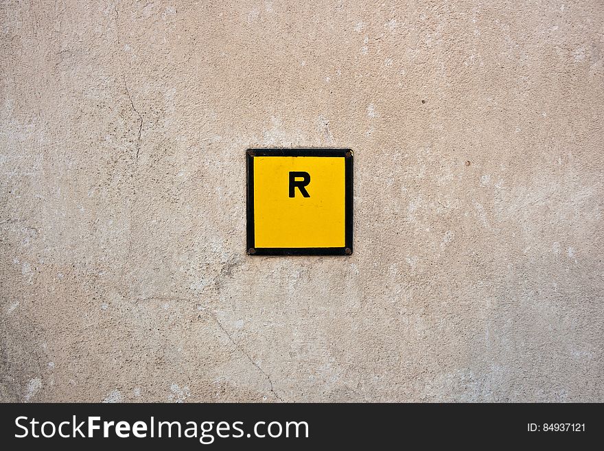 An R sign in a yellow square on a wall. An R sign in a yellow square on a wall.