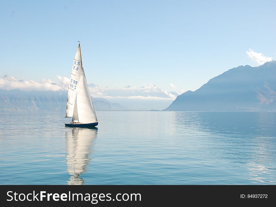 A sailboat in a bay reflecting on the water surface. A sailboat in a bay reflecting on the water surface.