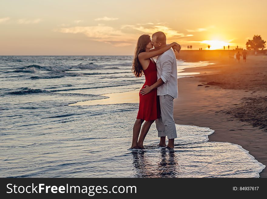 Romantic barefoot couple kissing on beach at sunset. Romantic barefoot couple kissing on beach at sunset.