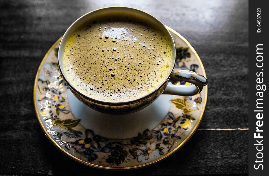 Elevated view of cup of coffee on porcelain saucer.