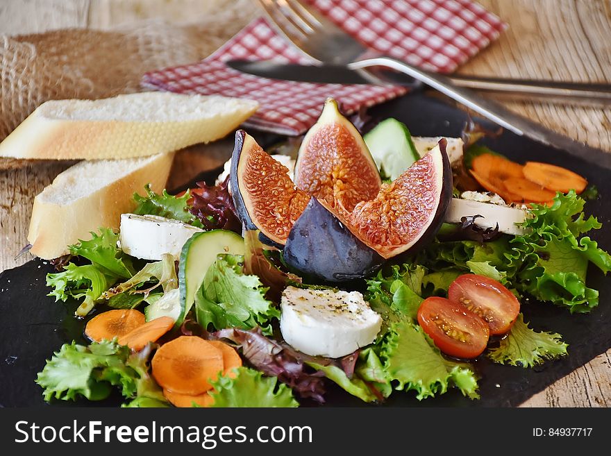 Fresh salad, cheese and bread on chopping board with cutlery and napkin. Fresh salad, cheese and bread on chopping board with cutlery and napkin.