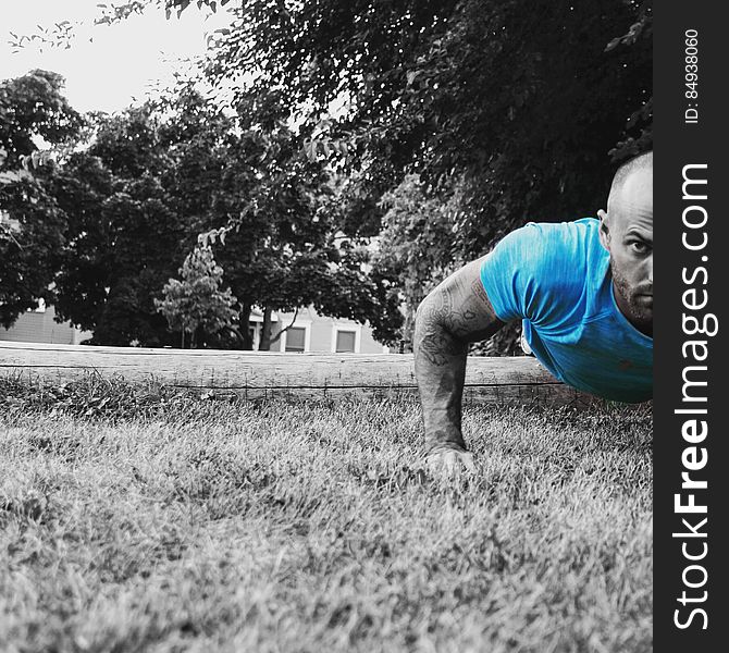 A man doing push ups on grass, selective color filter.