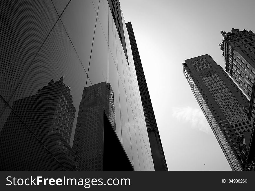 A view in a city with the facade of a glass skyscraper reflecting other buildings. A view in a city with the facade of a glass skyscraper reflecting other buildings.