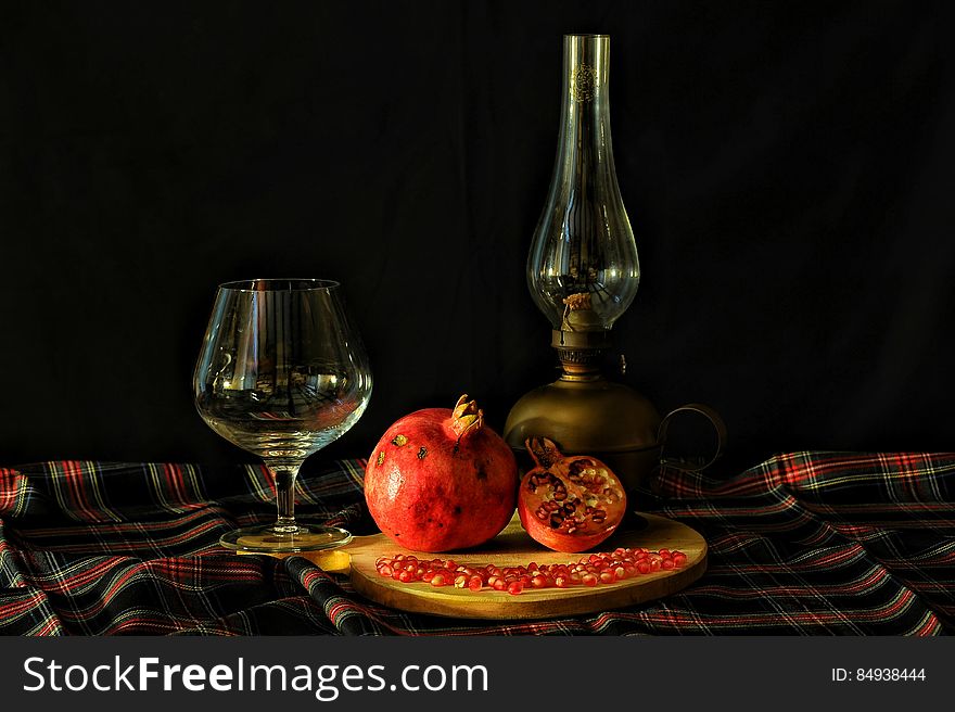 Ripe pomegranate fruit on table with whisky glass and retro style lamp. Ripe pomegranate fruit on table with whisky glass and retro style lamp.