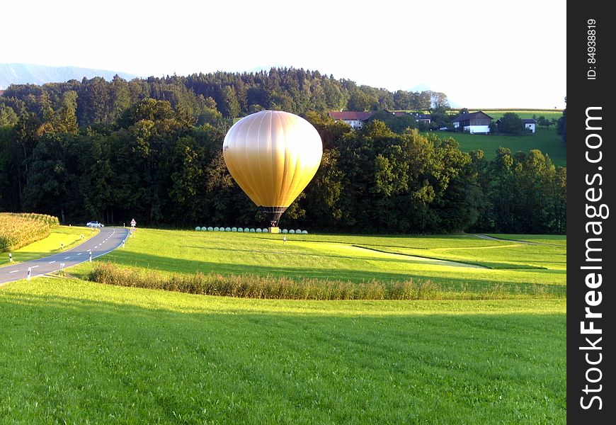 A golden hot air balloon above a green field.