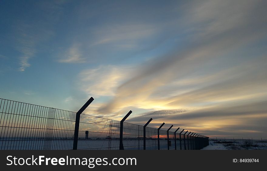 A cloudy sky above a fenceline at sunset. A cloudy sky above a fenceline at sunset.