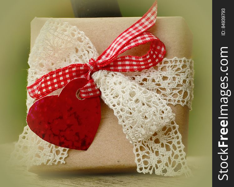 A gift box with an embroidered and plaid bow and a heart.