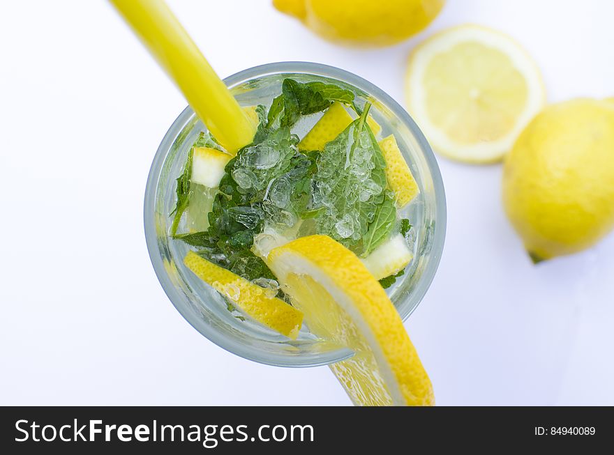 A drink with lemon and mint leaves in a glass.