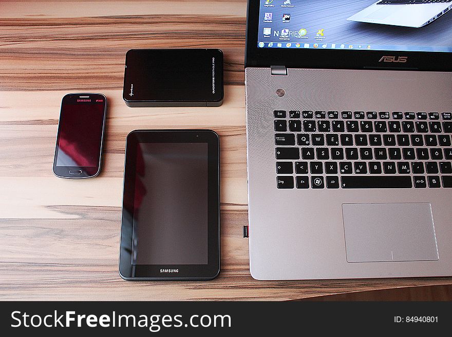 Various electronic devices on desk, laptop, tablet, mobile phone.