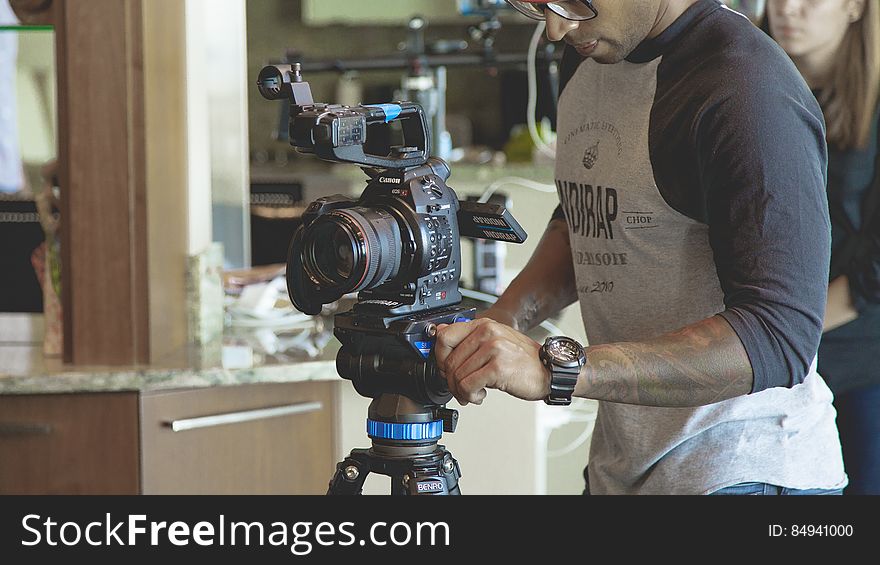 A photographer setting up a video camera on tripod.