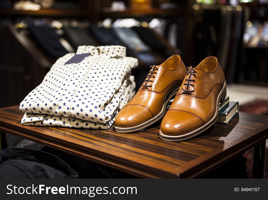 A pair of men's leather shoes and formal shirts in a shop. A pair of men's leather shoes and formal shirts in a shop.