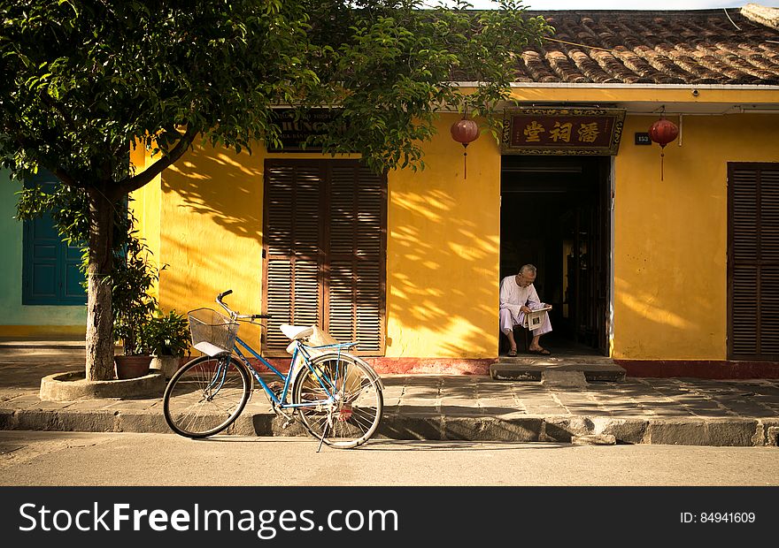 Asian Home With Man Reading Paper And Bicycle