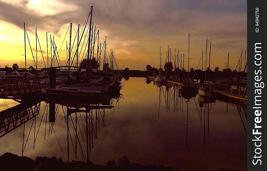 Sailboats in marina reflecting in water at sunset. Sailboats in marina reflecting in water at sunset.