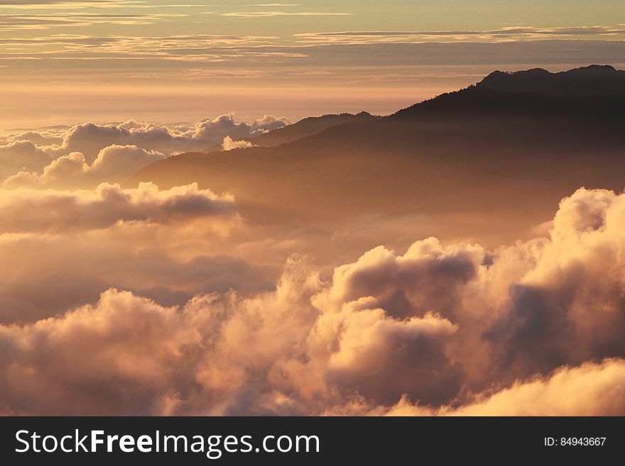 Silhouette of Mountain With Fluffy Clouds during Sunset