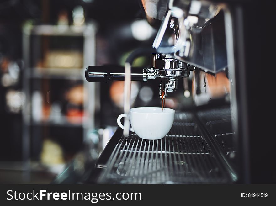 A view of a modern coffee shop with espresso dripping from the espresso machine. A view of a modern coffee shop with espresso dripping from the espresso machine.
